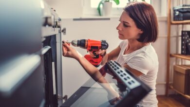 Woman working on a new kitchen installation and using a cordless drill