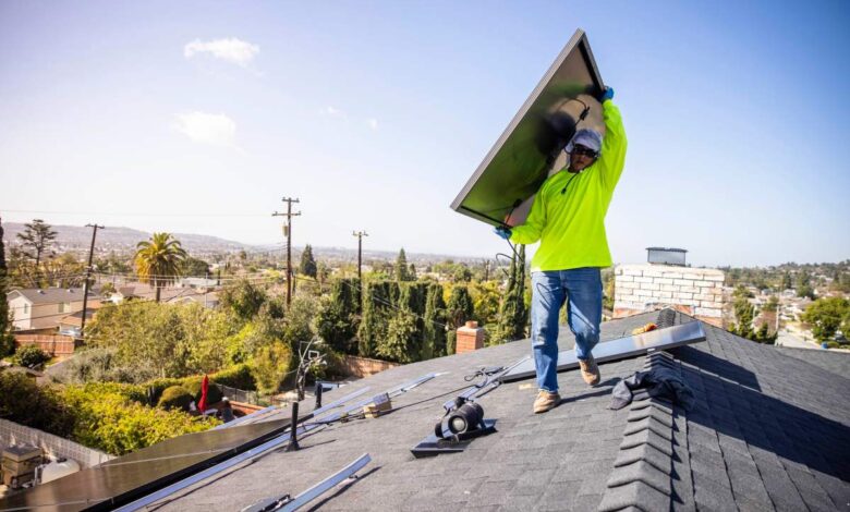 Man carrying a solar panel on a roof in Southern California.