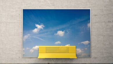 Yellow bench in front of billboard with sky and clouds