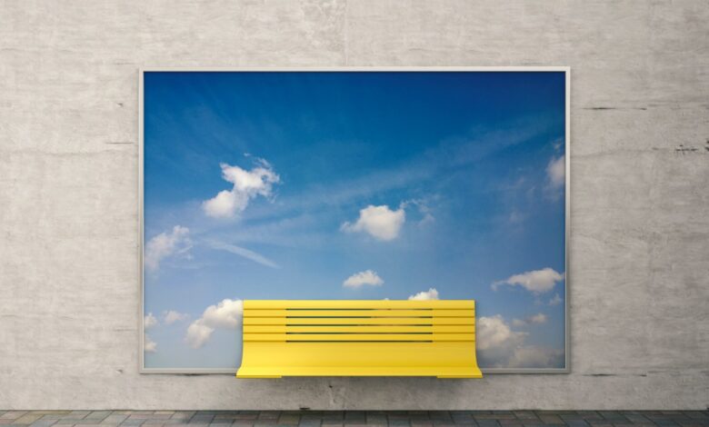 Yellow bench in front of billboard with sky and clouds