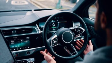 person's hands letting go of steering wheel of self-driving car
