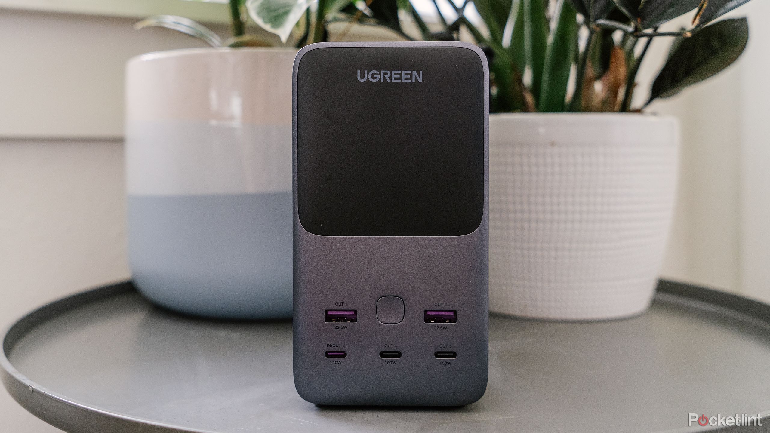 پاوربانک Ugreen 300W 48000mAh روی میز جلوی گیاهان گلدانی. 