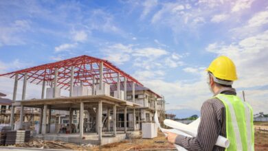 Professional engineer architect worker with protective helmet and blueprints paper at house building construction site background