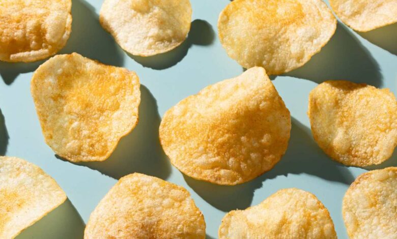 Potato chips sit against a light blue table.