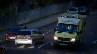 Seen from a high perspective, a London Ambulance passes an oncoming car at dusk on a residential street in Lambeth, south London, on 27th October 2023