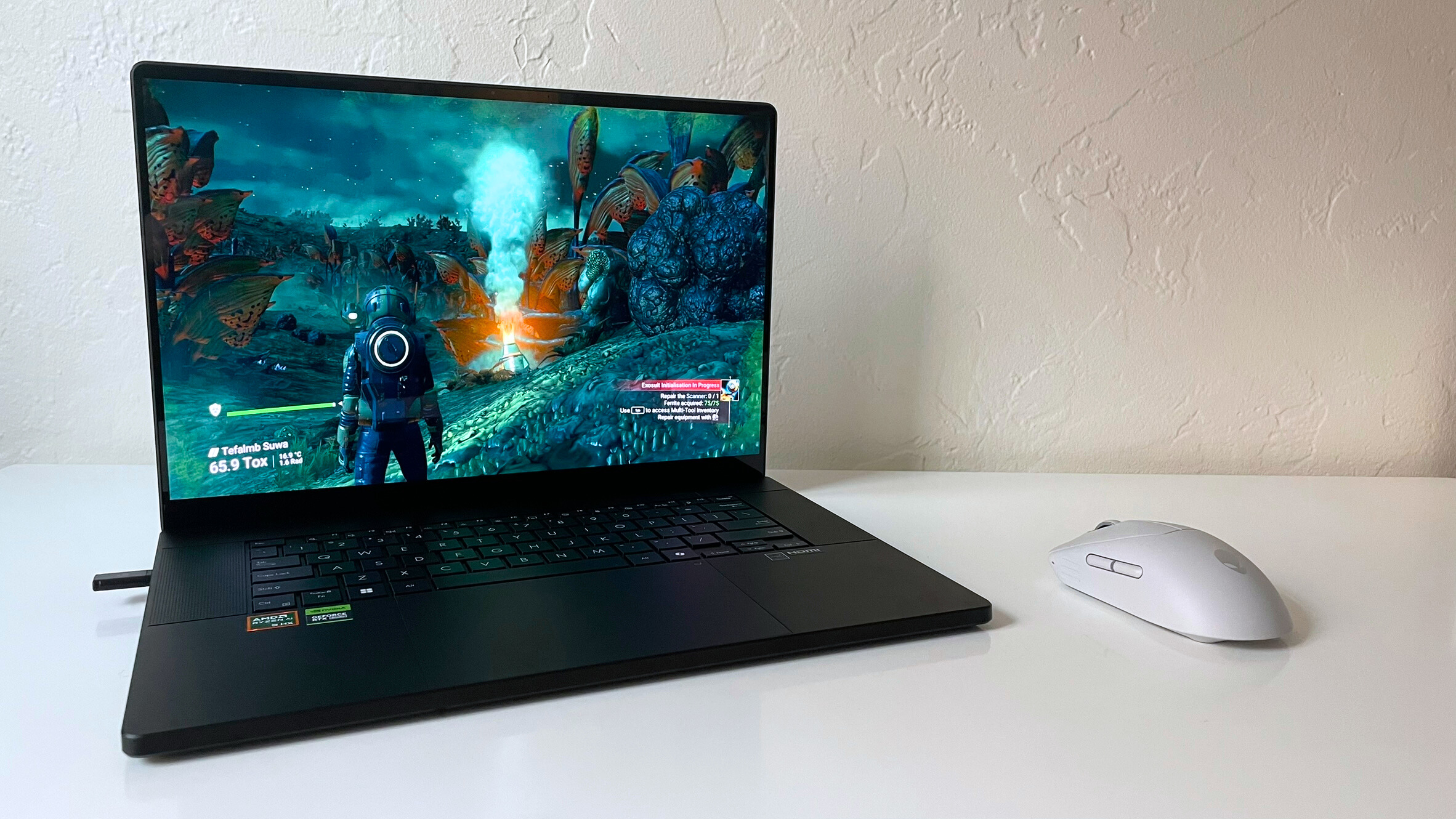 ASUS ProArt P16 در حال اجرا No Man's Sky (Hello Games) روی یک میز سفید در کنار یک ماوس خاکستری
