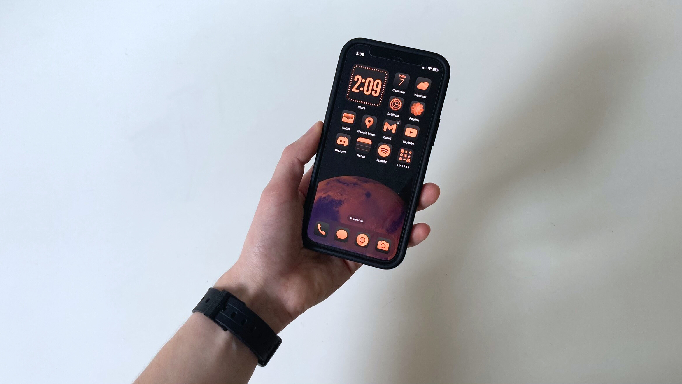 دست شخصی که آیفونی را در دست دارد و صفحه اصلی iOS 18 را نشان می دهد
