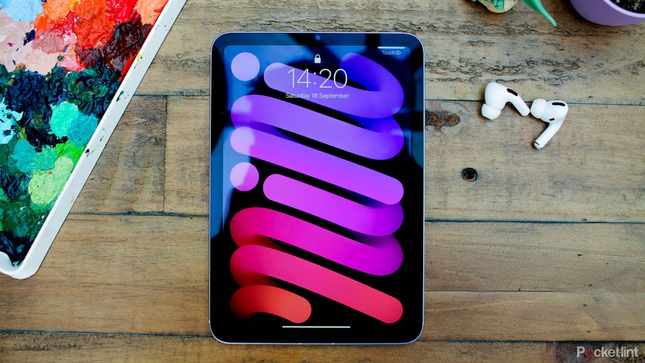 iPad mini روی میز چوبی با AirPods Pro.