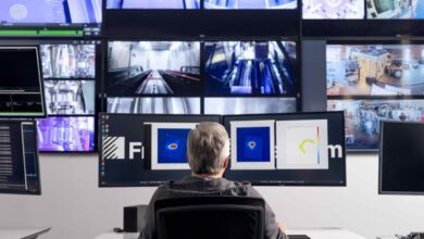 Man sitting in front of multiple large computer monitors.
