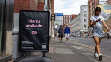 Members of the public pass by a floor advertisement for tech firm Klarna.