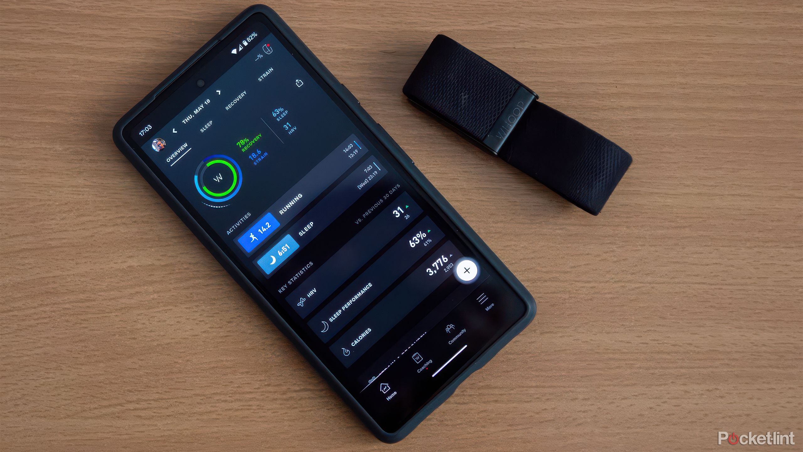 تلفنی با برنامه Whoop و Whoop 4.0 روی میز چوبی قرار دارد. 