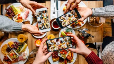 Friends taking pictures of food on the table with smartphones during brunch in restaurant