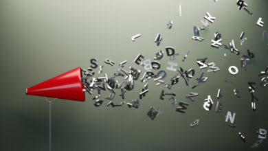 Red megaphone and silver colored alphabet letters in front of gray wall. Horizontal composition with copy space. Great use for announcement concepts.