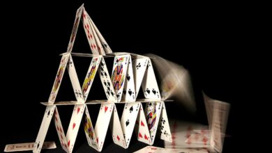 A house of cards collapsing on dark background