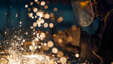 A metalworker cuts steel in a workshop.