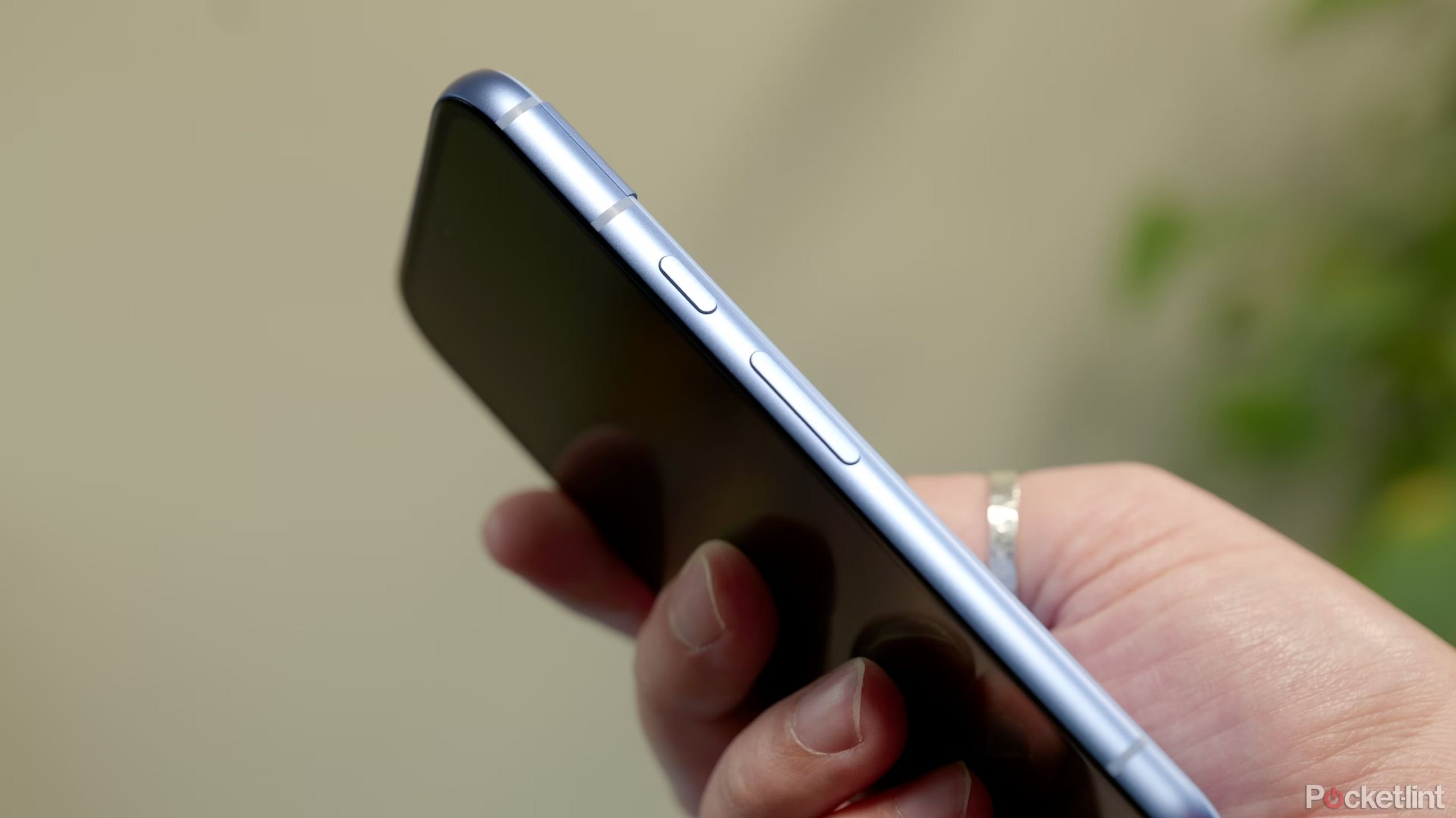 Pixel 8a در دست با نزدیک شدن در دکمه های جانبی از نزدیک.