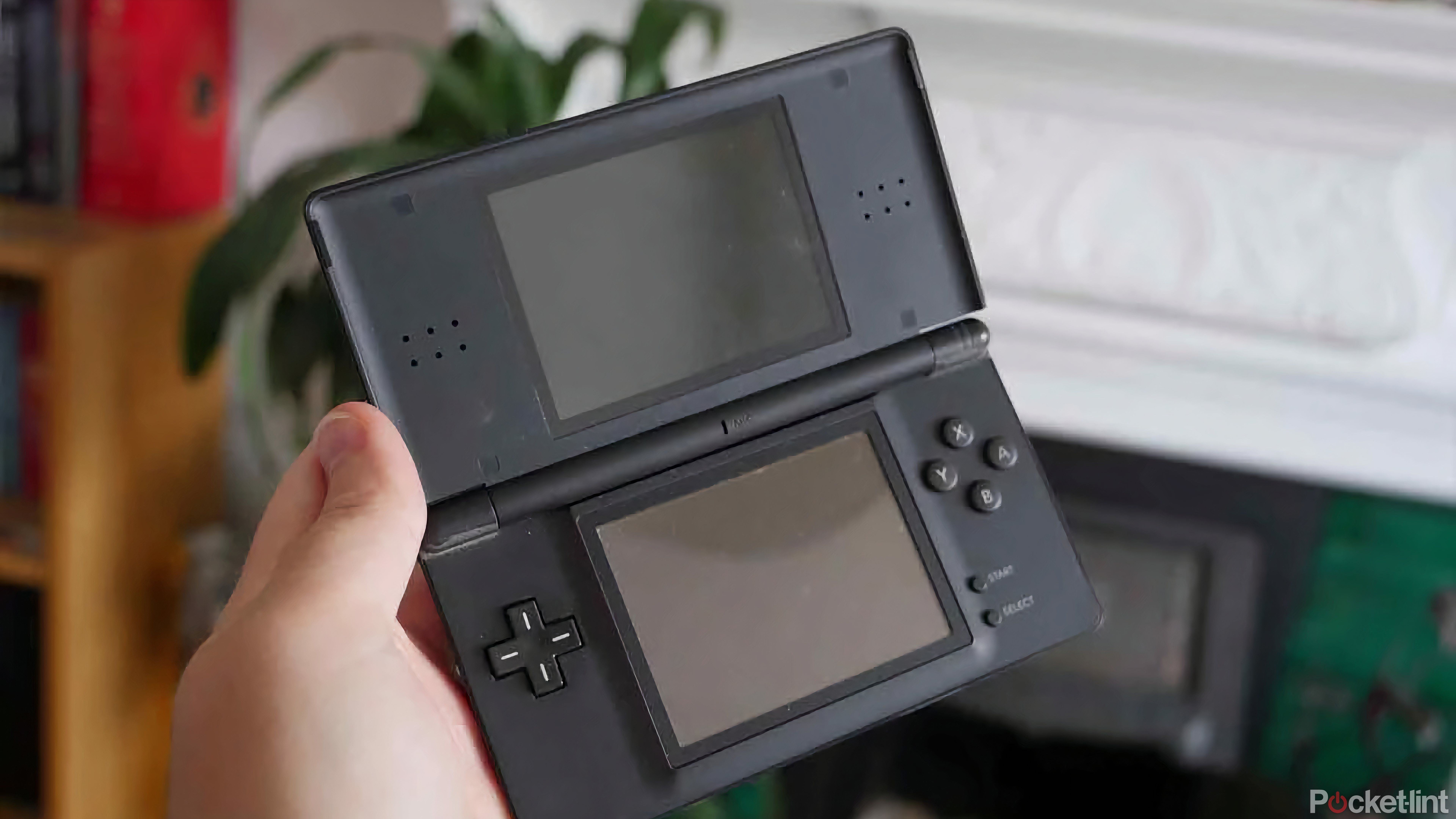 دستی که دارای یک Nintendo DS Lite سیاه و سفید با صفحه نمایش خود است.