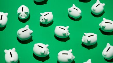 16 small white piggy banks placed randomly on green surface, high angle of view