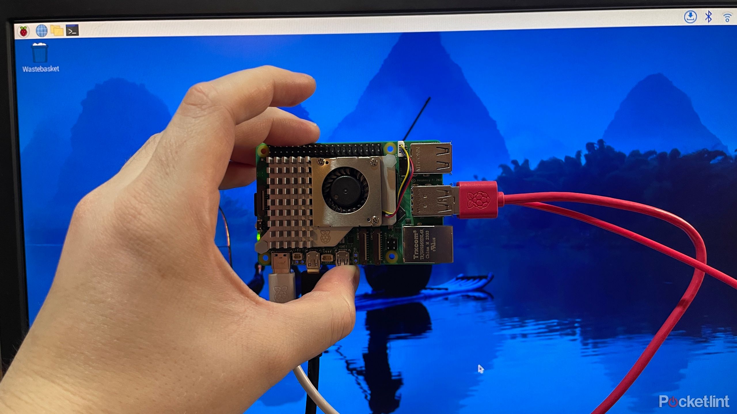 Raspberry Pi 5 که در مقابل صفحه نمایش با Raspberry Pi Os برگزار می شود