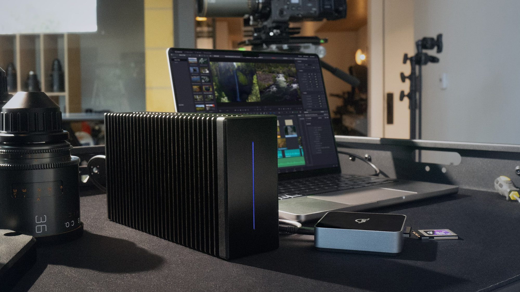 OWC Thunderblade X12 که روی میز کنار یک MacBook Pro و Gear Camera نشسته است.