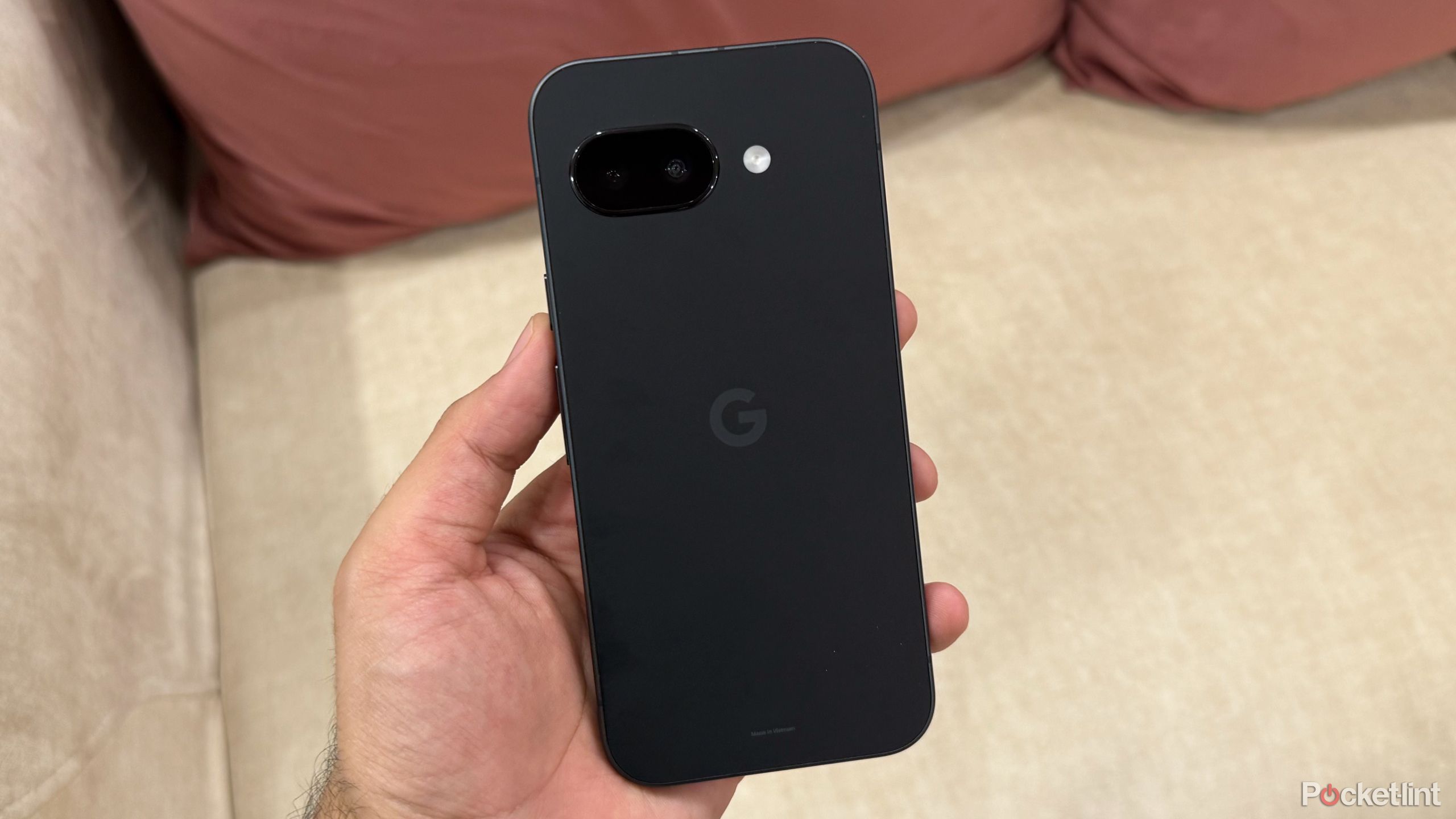 Google Pixel 9a در مقابل یک مبل سفید