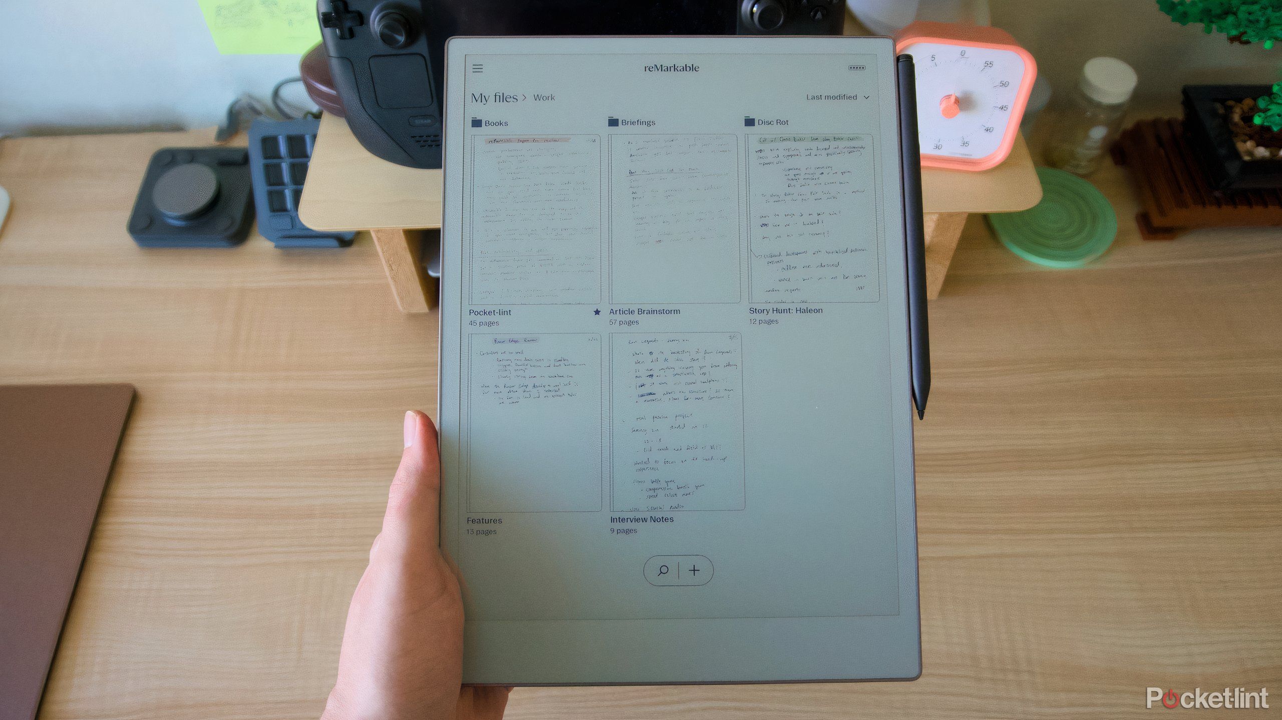 دستی که یک کاغذ قابل توجه را روی یک میز نگه می دارد.