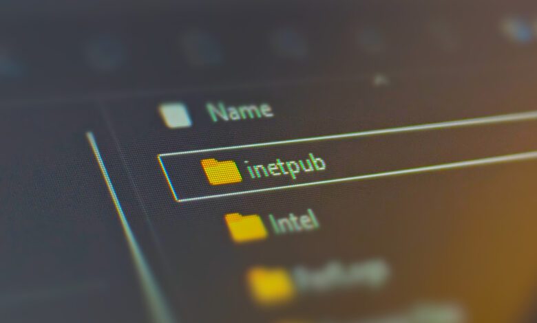 Photograph focusing on a laptop screen showing the 'inetpub' folder in Windows 11's system drive.
