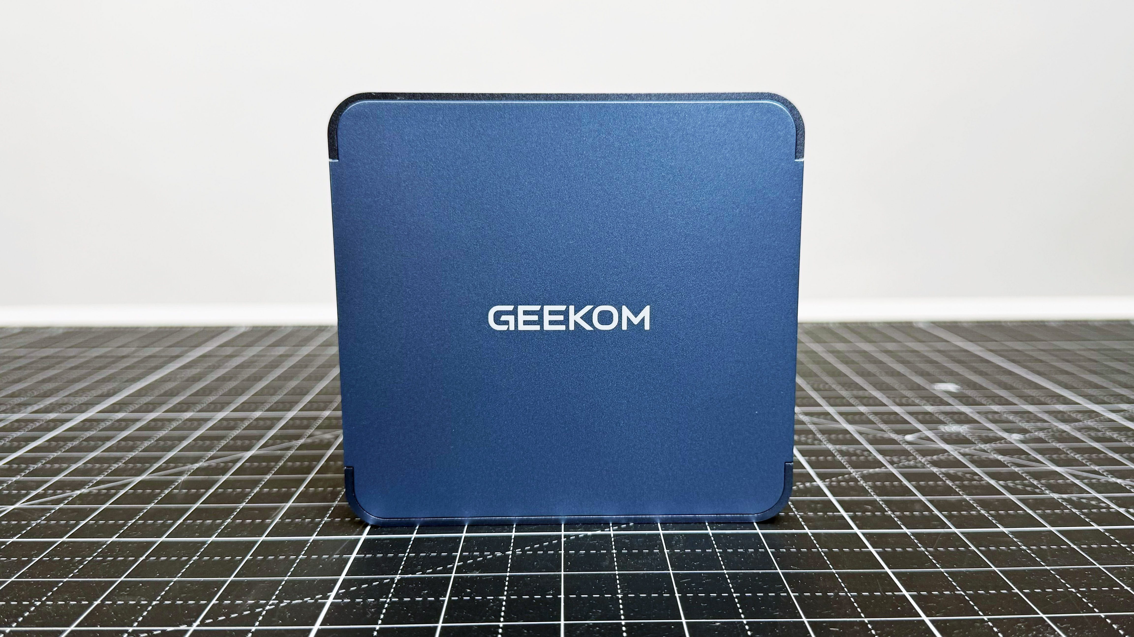 Geekom Ax8 Pro Ai Mini PC روی یک تشک سیاه در برابر پس زمینه سفید ایستاده است.