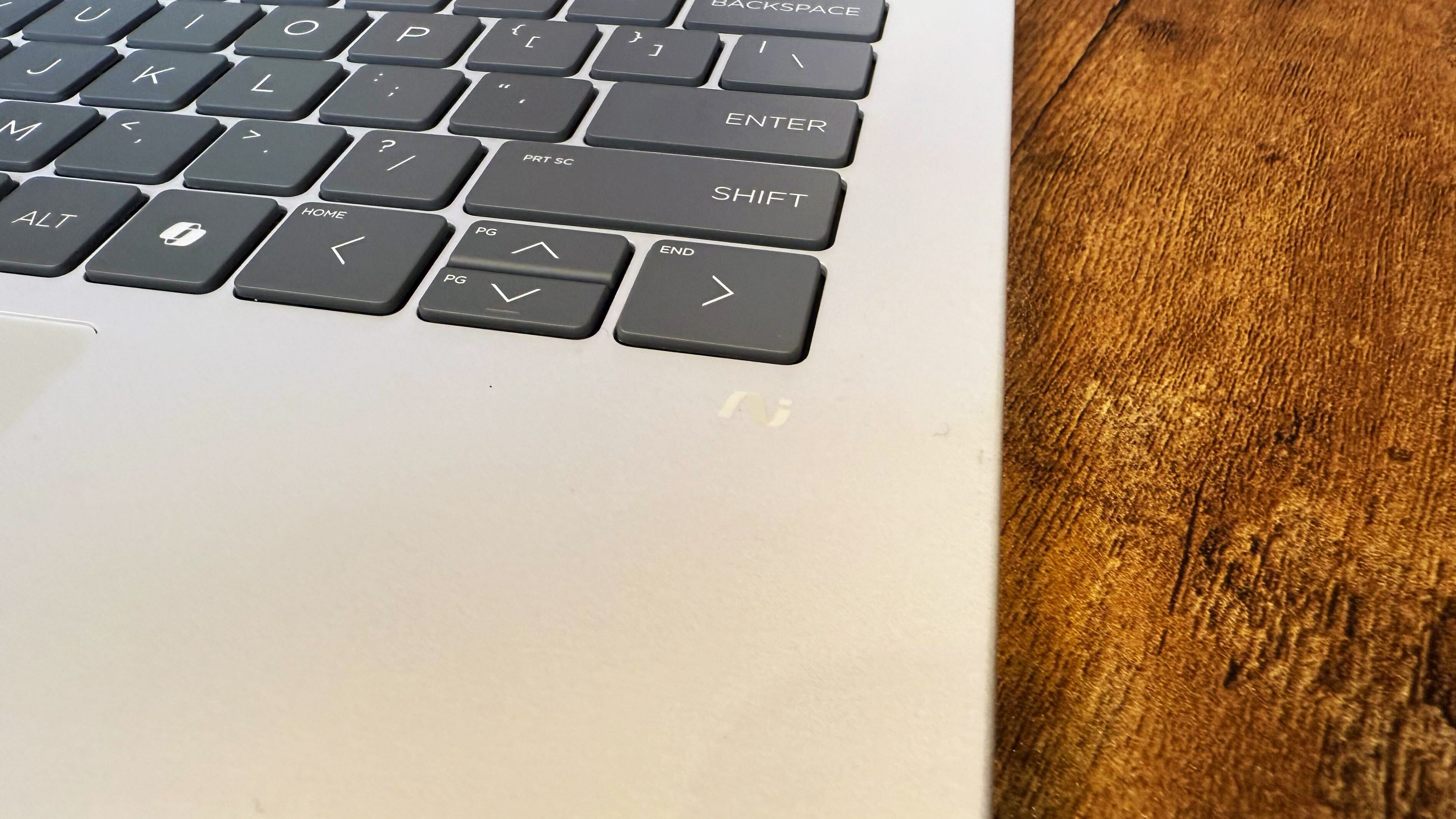 HP Omnibook 5 14 AI PC روی یک میز چوبی در برابر پس زمینه سیاه.