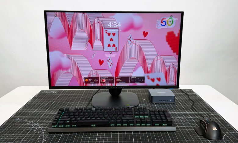 Geekom AX8 Pro AI Mini PC set up with a monitor, keyboard, and mouse, on a black mat against a white background.
