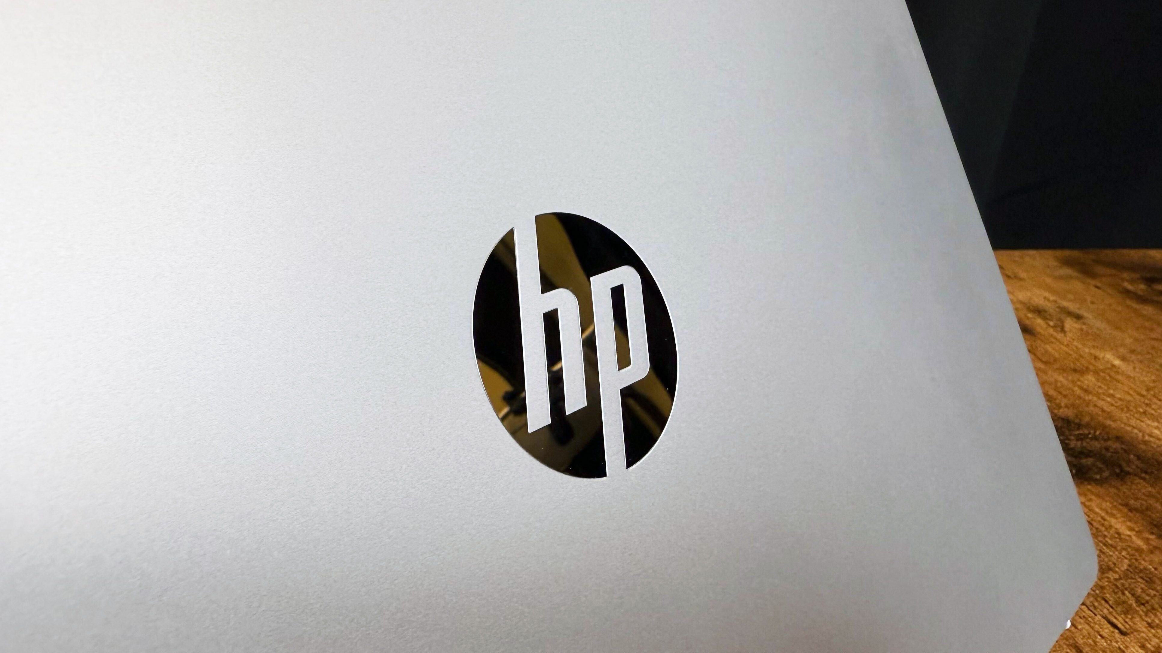 HP Omnibook 5 14 AI PC روی یک میز چوبی در برابر پس زمینه سیاه.