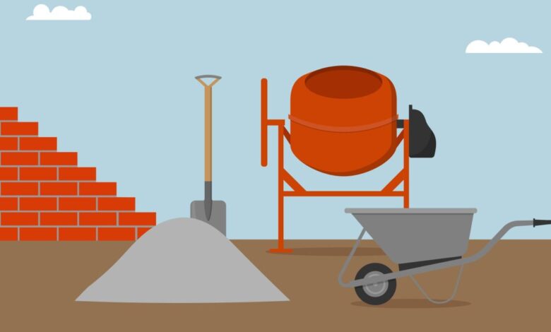Brick wall, concrete mixer, wheelbarrow, bucket and spade.