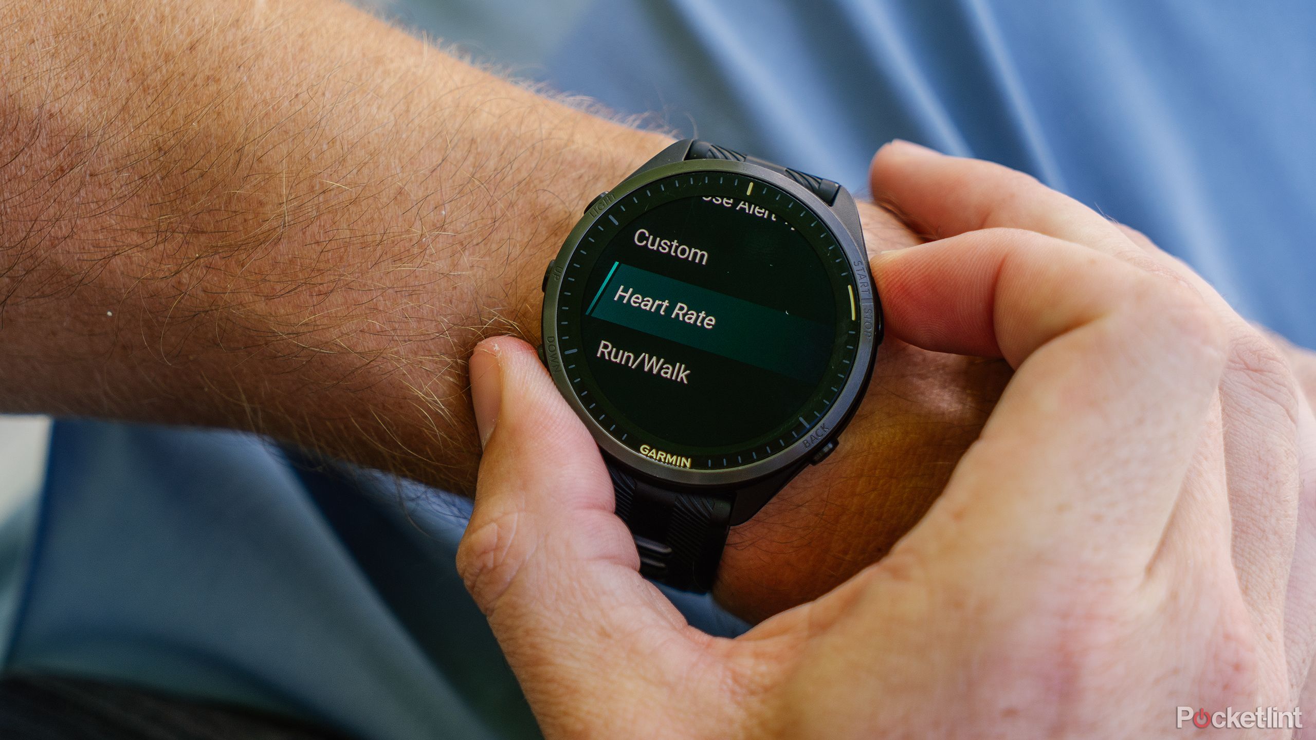در حالی که روی مچ دست است ، دکمه ای را روی Garmin Forerunner 965 فشار می دهد.