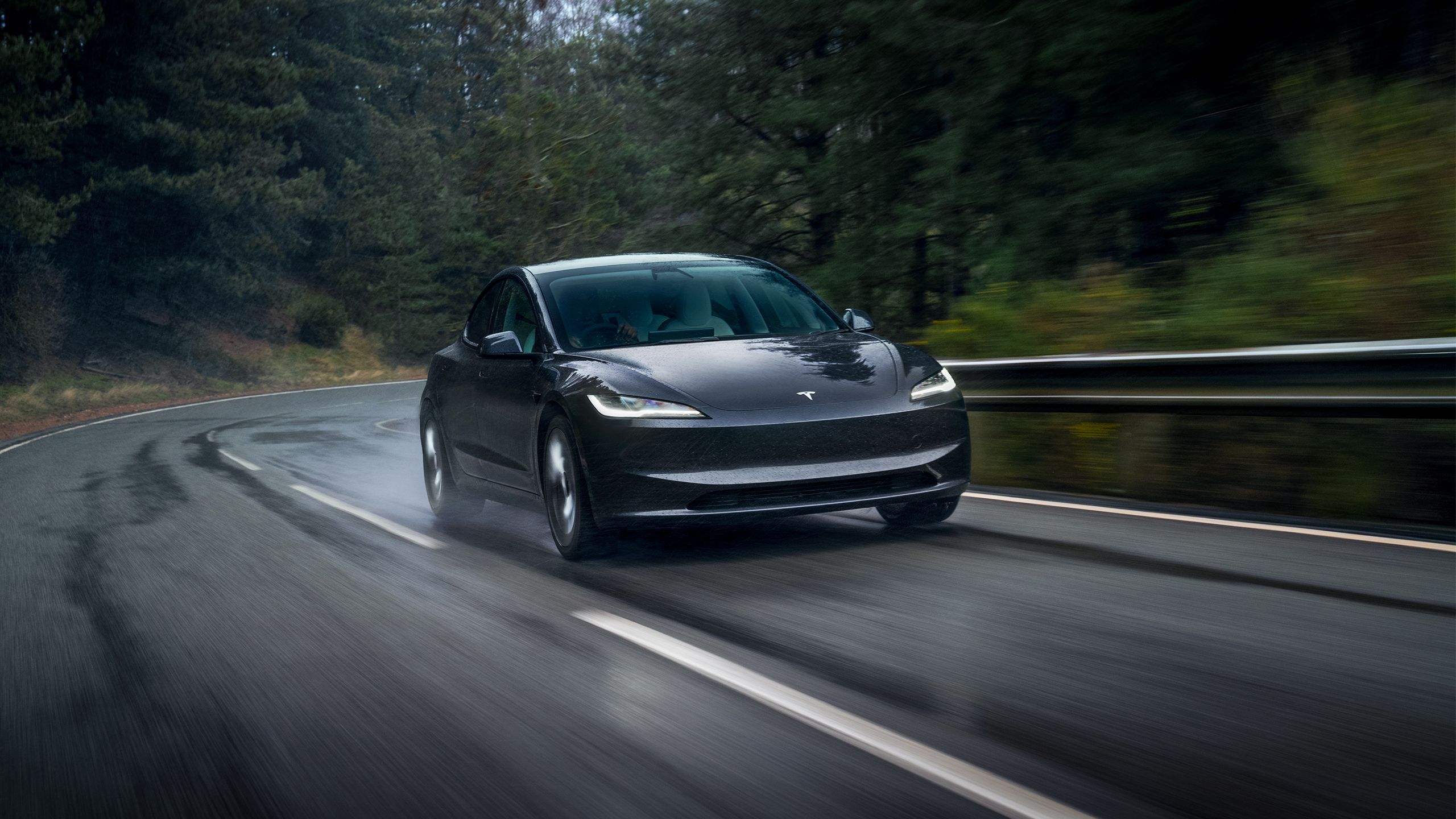 یک خاکستری تیره 2024 Tesla Model 3 در امتداد بزرگراه ساحل اقیانوس آرام حرکت می کند.