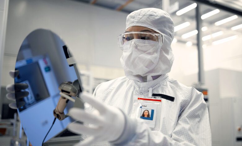 An Intel Foundry engineer in clean room gear holds a silicon wafer at an Intel facility in Chandler, Arizona.