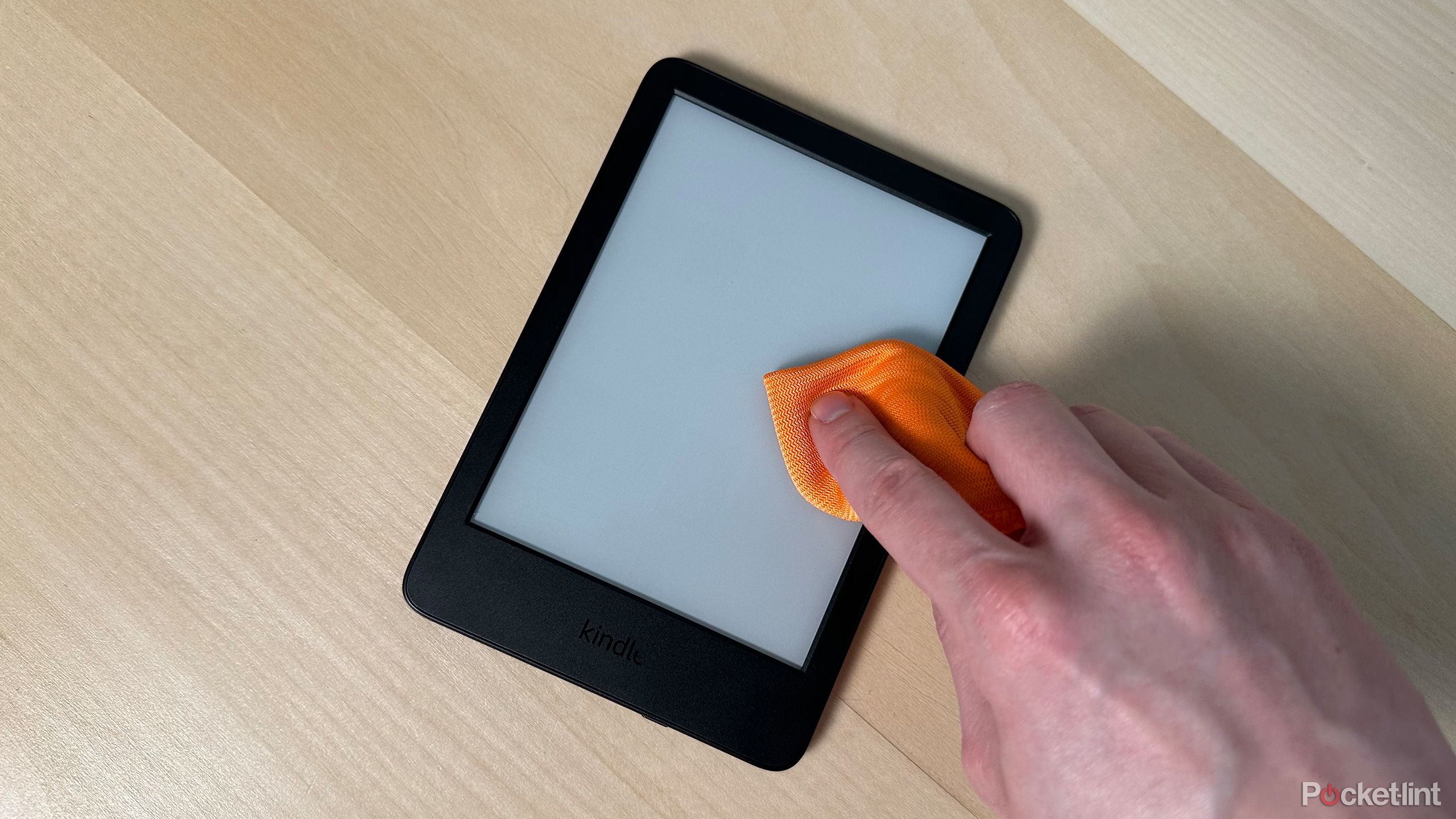 تمیز کردن صفحه Kindle با پارچه میکرو فیبر نارنجی.
