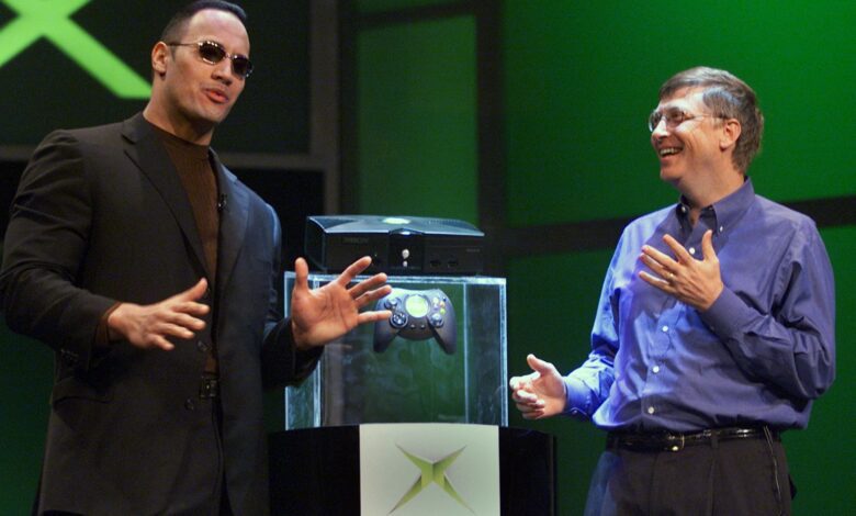 Bill Gates of Microsoft (R) speaks with World Wrestling Federation star "The Rock" after Gates unveiled the new Xbox video game console at the Consumer Electronics Show in Las Vegas 06 January 2001. "The Rock" will be featured in a video game when the Xbox launches in the fall of 2001. AFP PHOTO/Jeff Christensen (Photo by JEFF CHRISTENSEN / AFP) (Photo by JEFF CHRISTENSEN/AFP via Getty Images)