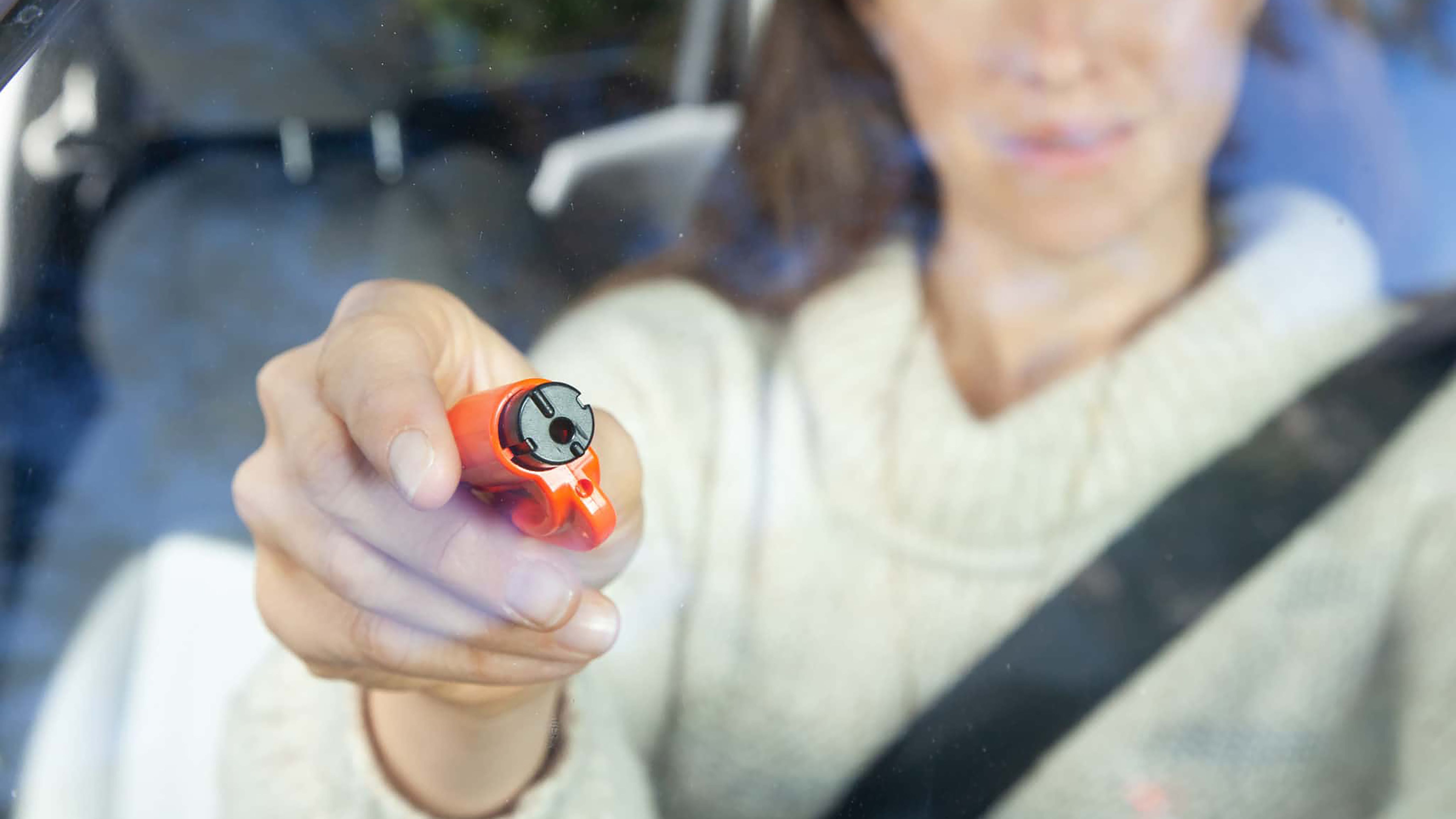 زنی که یک ابزار شکن شیشه ای Resqme را به یک پنجره در اختیار دارد.