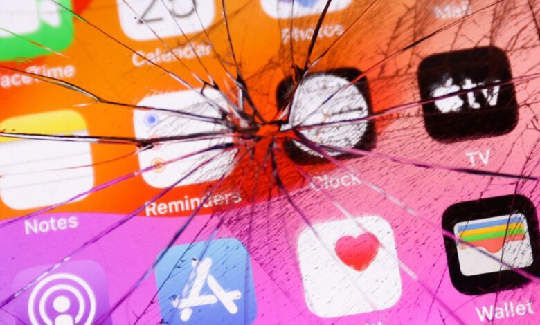 App icons displayed on a phone screen are seen through the broken glass in this illustration photo.