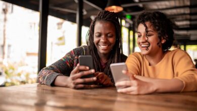 Photo of two friends sending money to each other through a digital wallet on their smartphones