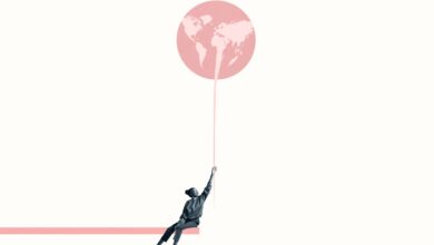 Young woman holding at large pink balloon with world map while sitting on ramp against white background