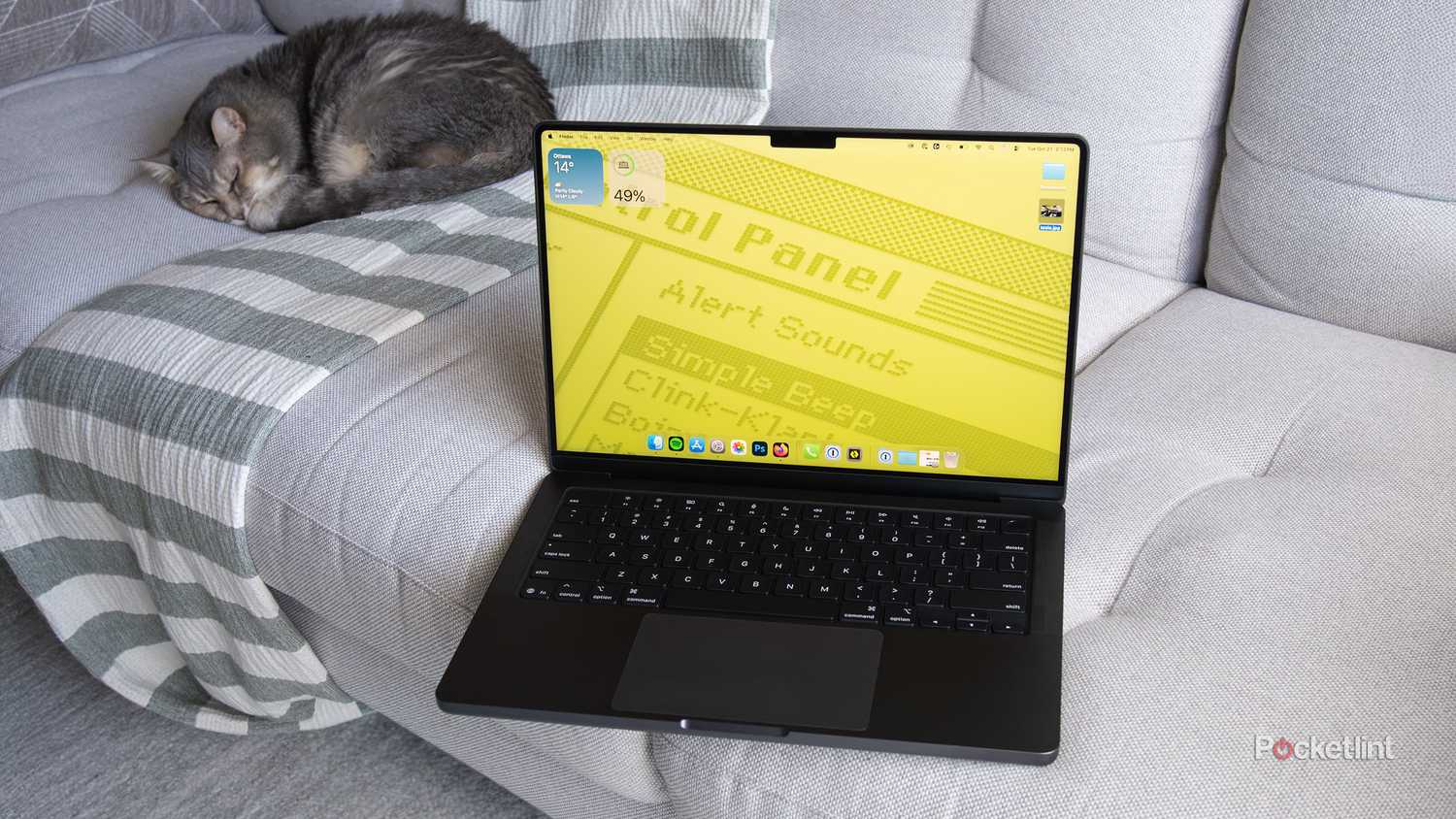 M5 MacBook Pro روی کاناپه ای با پس زمینه رترو نشسته است 