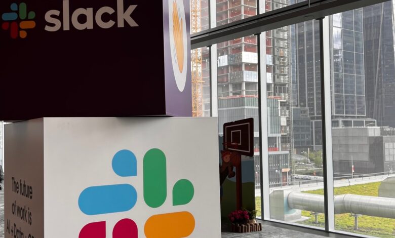 Cubes with Slack name and logo stacked on one another with city view in background.
