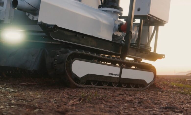 An autonomous, tracked robot sits on a dirt patch.